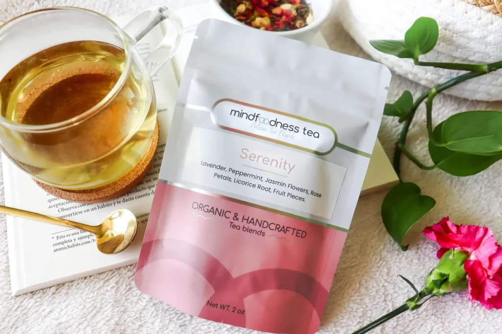 Serenity Tea pouch beside a glass cup of tea and fresh flowers
