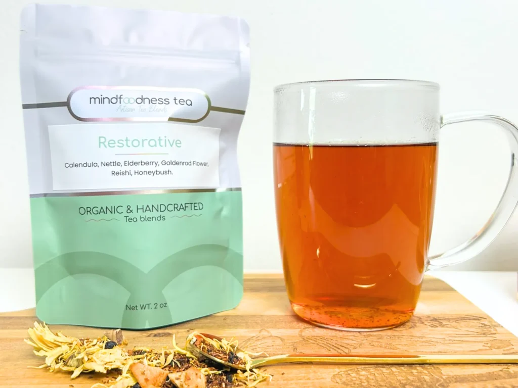 Restorative Tea pouch beside a glass mug of amber tea